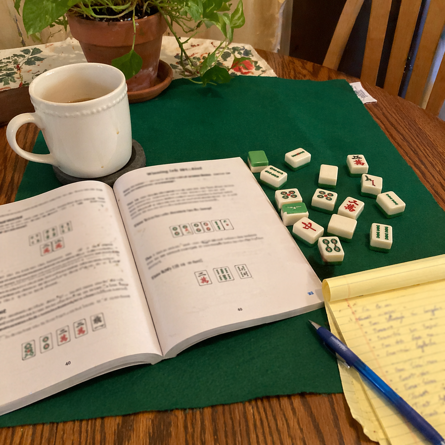 Lived-in study scene with Mah Jongg tiles, books, and strategy materials