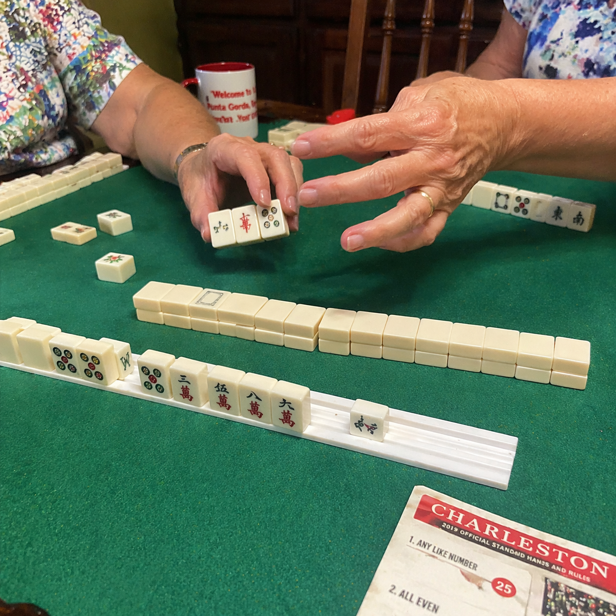 Hands arranging tiles during the Charleston in American Mah Jongg